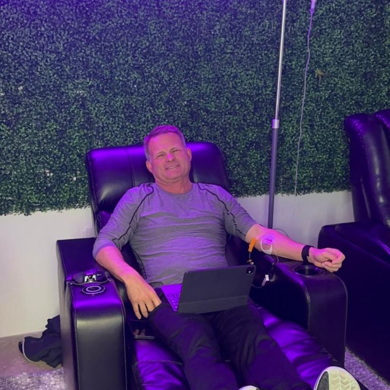 A client working on his tablet in a recliner during an IV drip